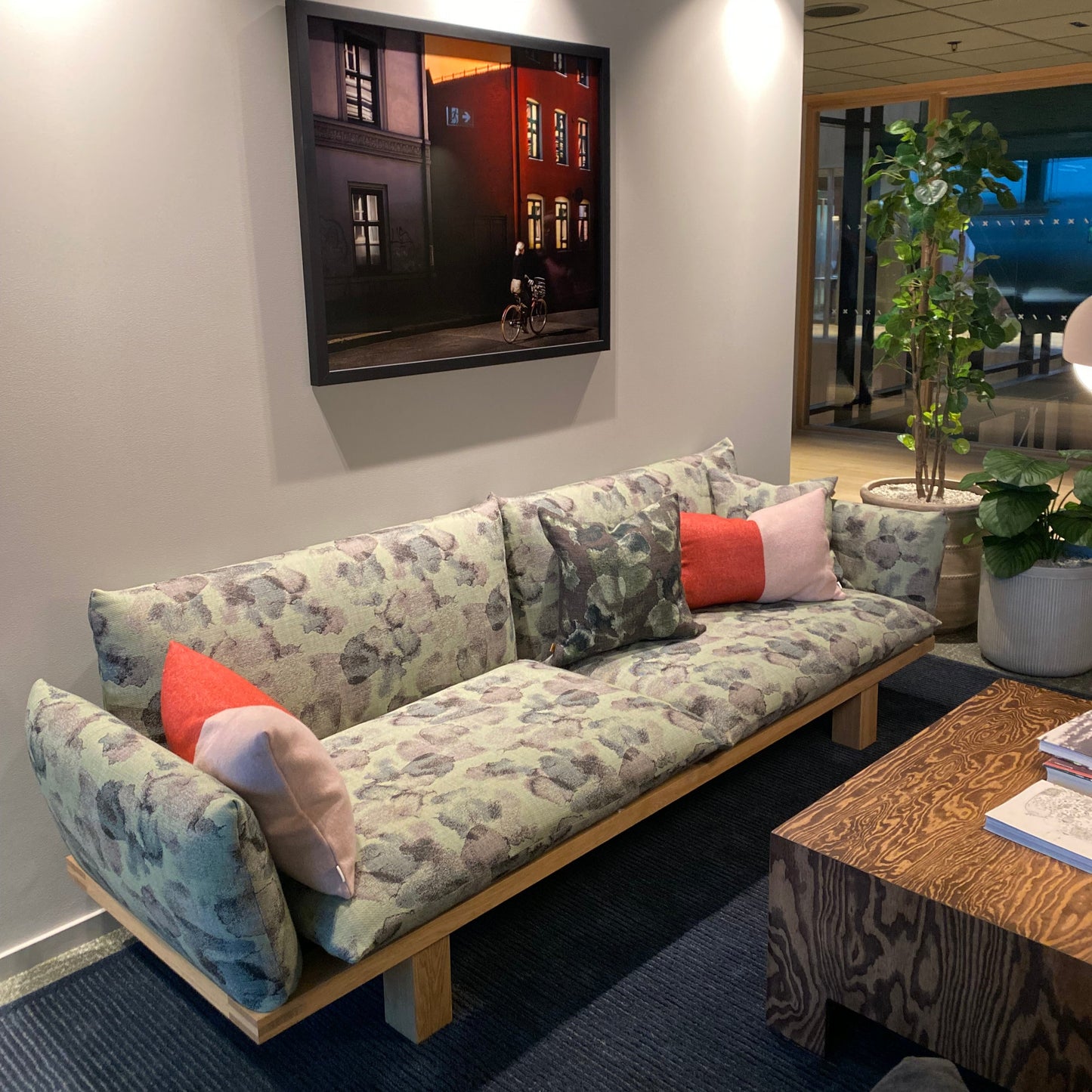 Floral-patterned sofa with colorful cushions in a room with a painting on the wall.