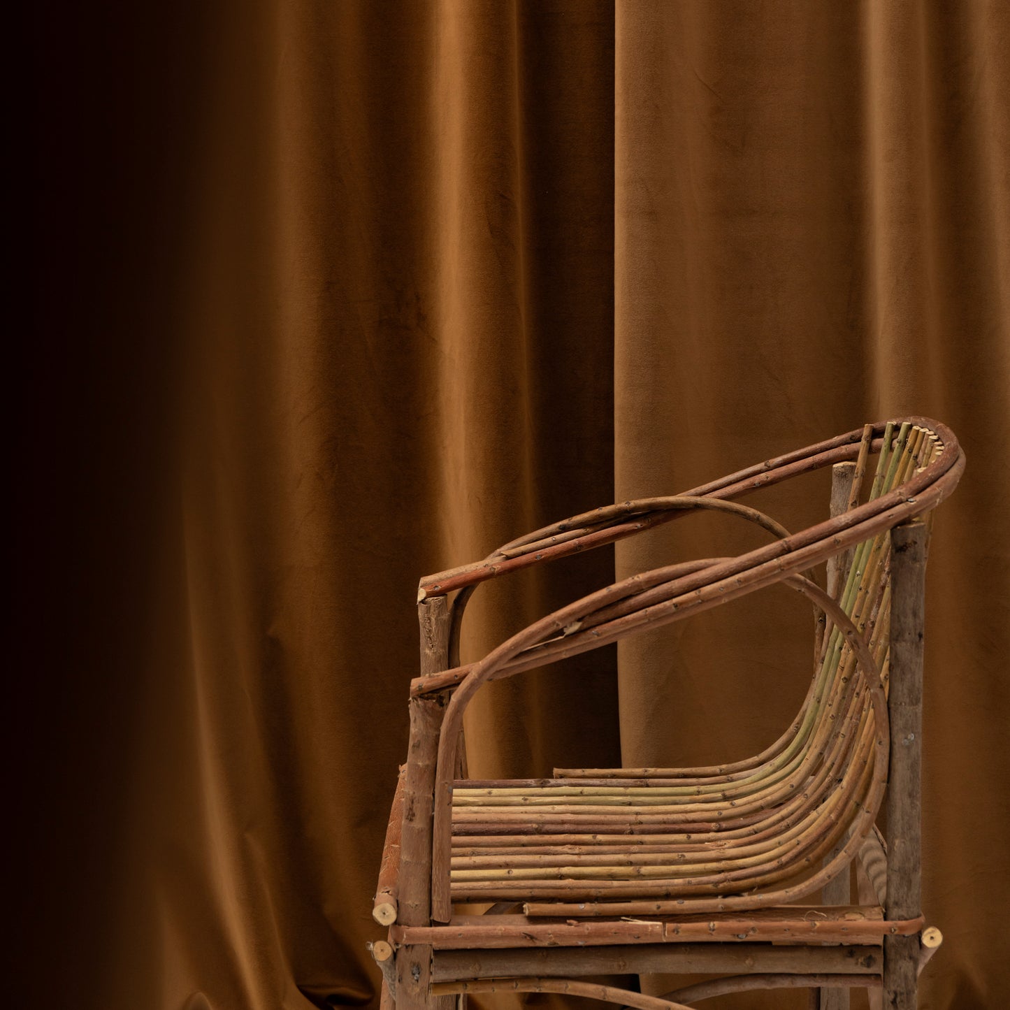 side view of natura chair made from oleandre branches with brown curtain background