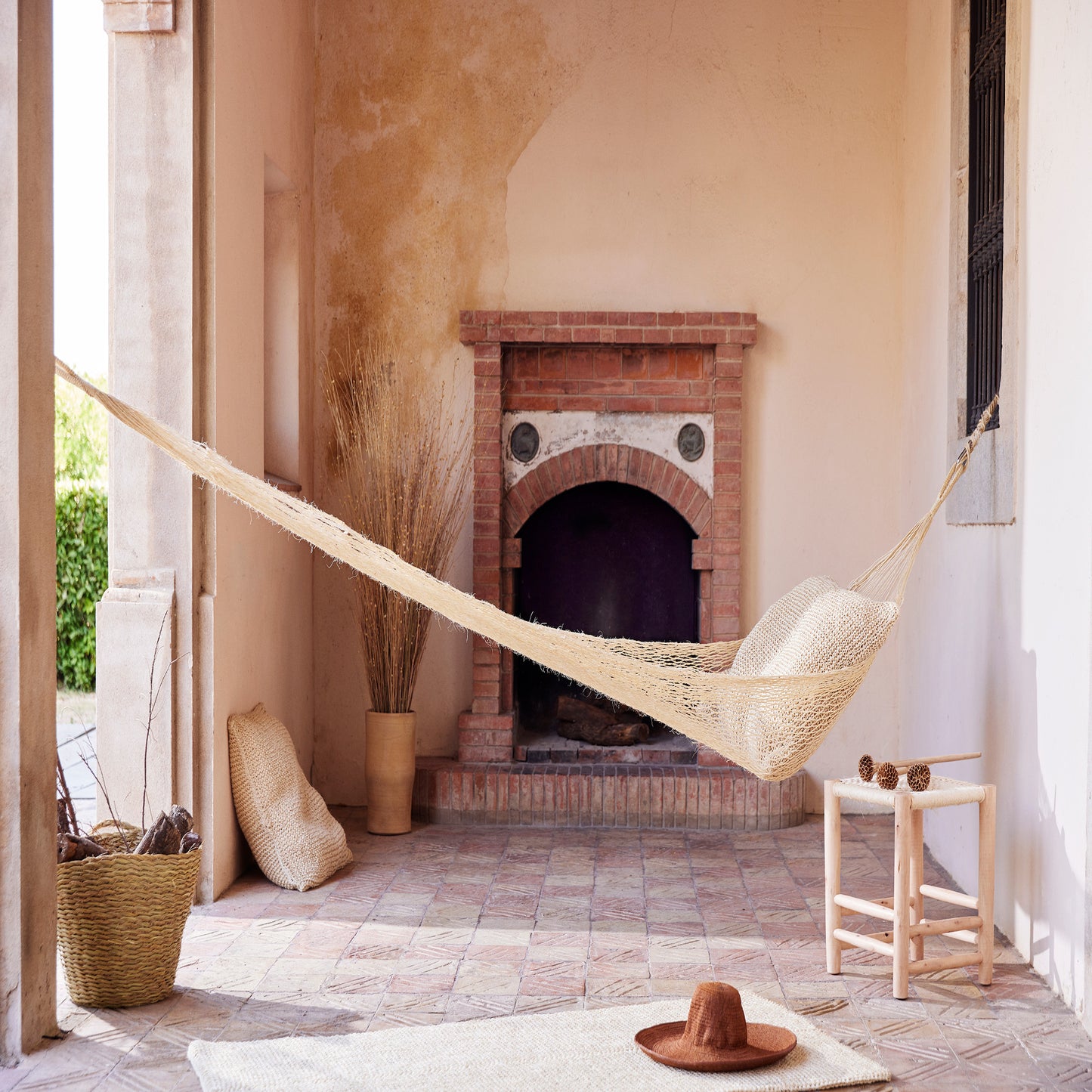 Albeira Hammock in a cozy outdoor setting with a fireplace and decorative elements.