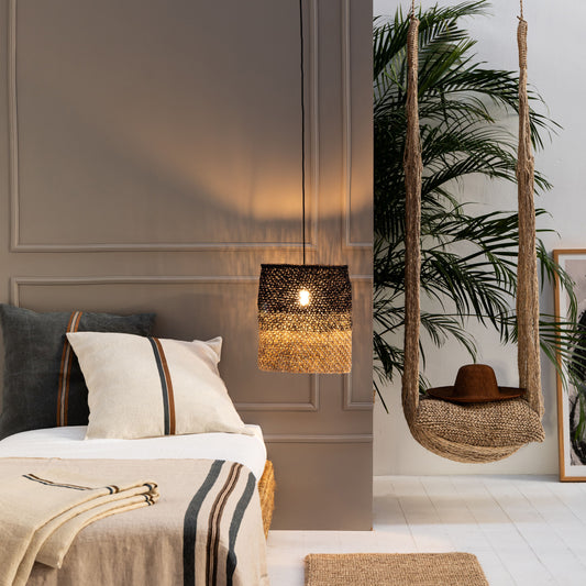 Cozy bedroom with a bed, hanging plant, swing in natural fibres with cushion and hat ,  decorative lamp in naural fibres