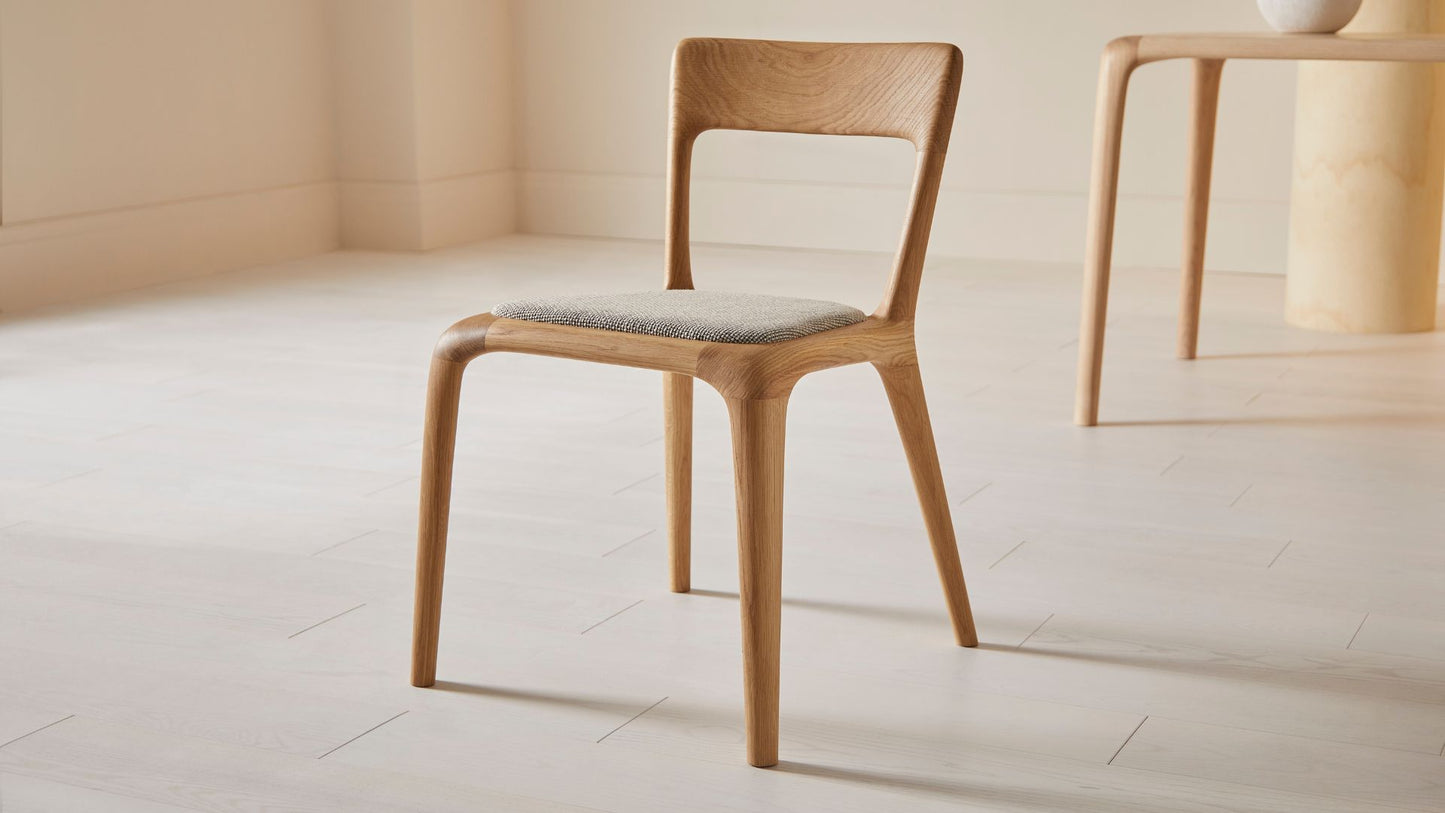 Flow dining chair in natural ash with an upholstered seat