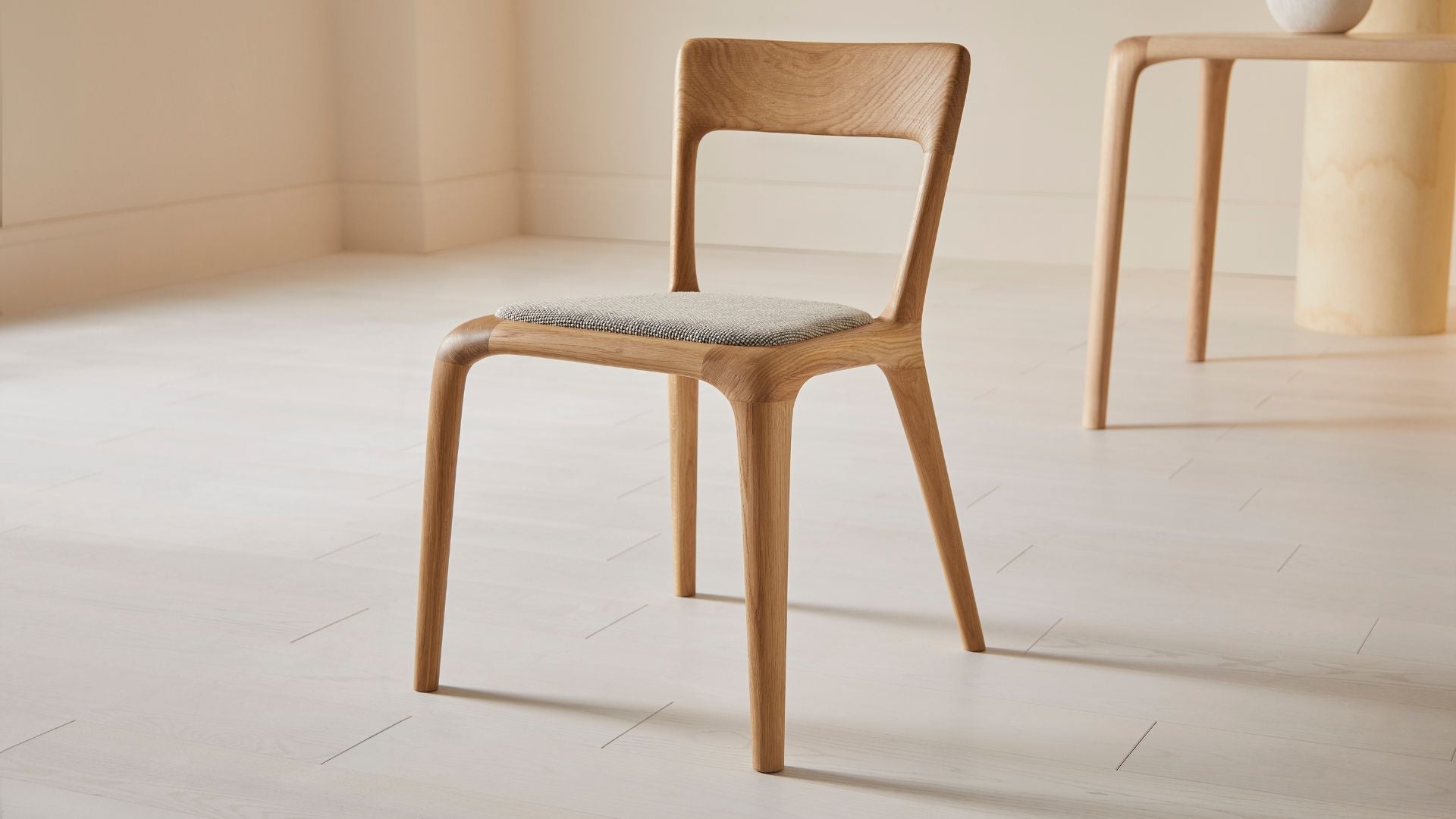 Flow dining chair in natural ash with an upholstered seat