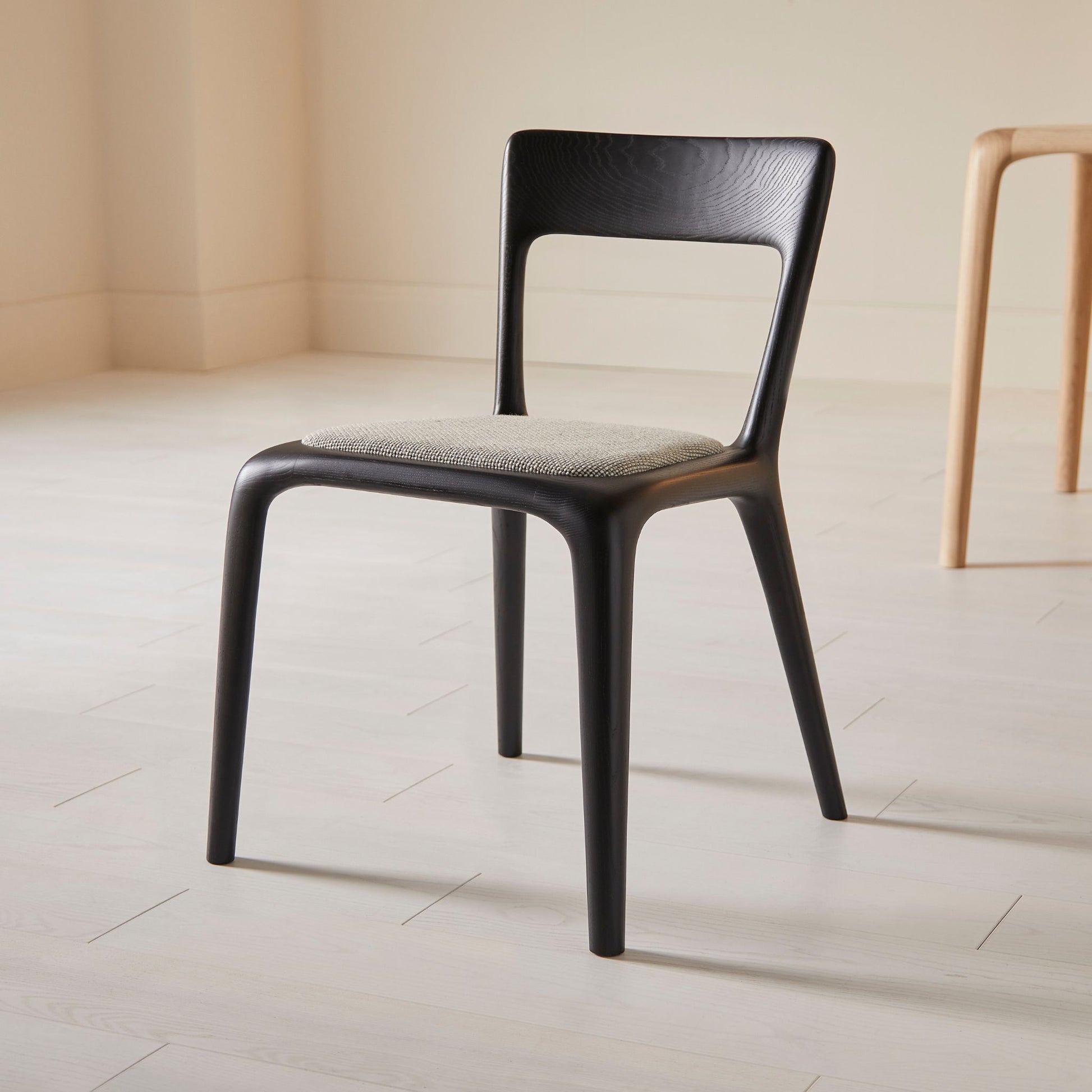 Flow dining chair in ebonised ash with an upholstered seat