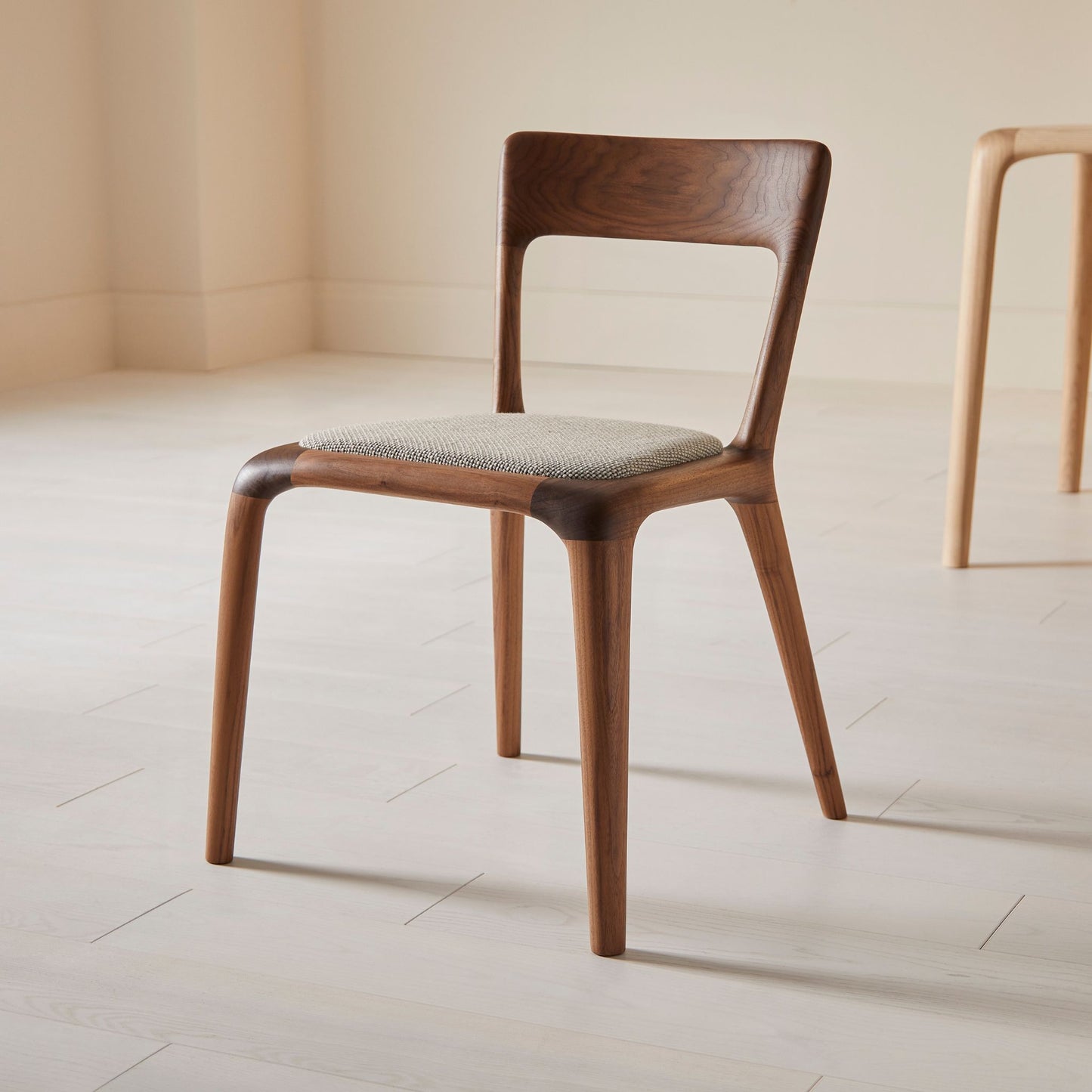 Flow dining chair in walnut with an upholstered seat