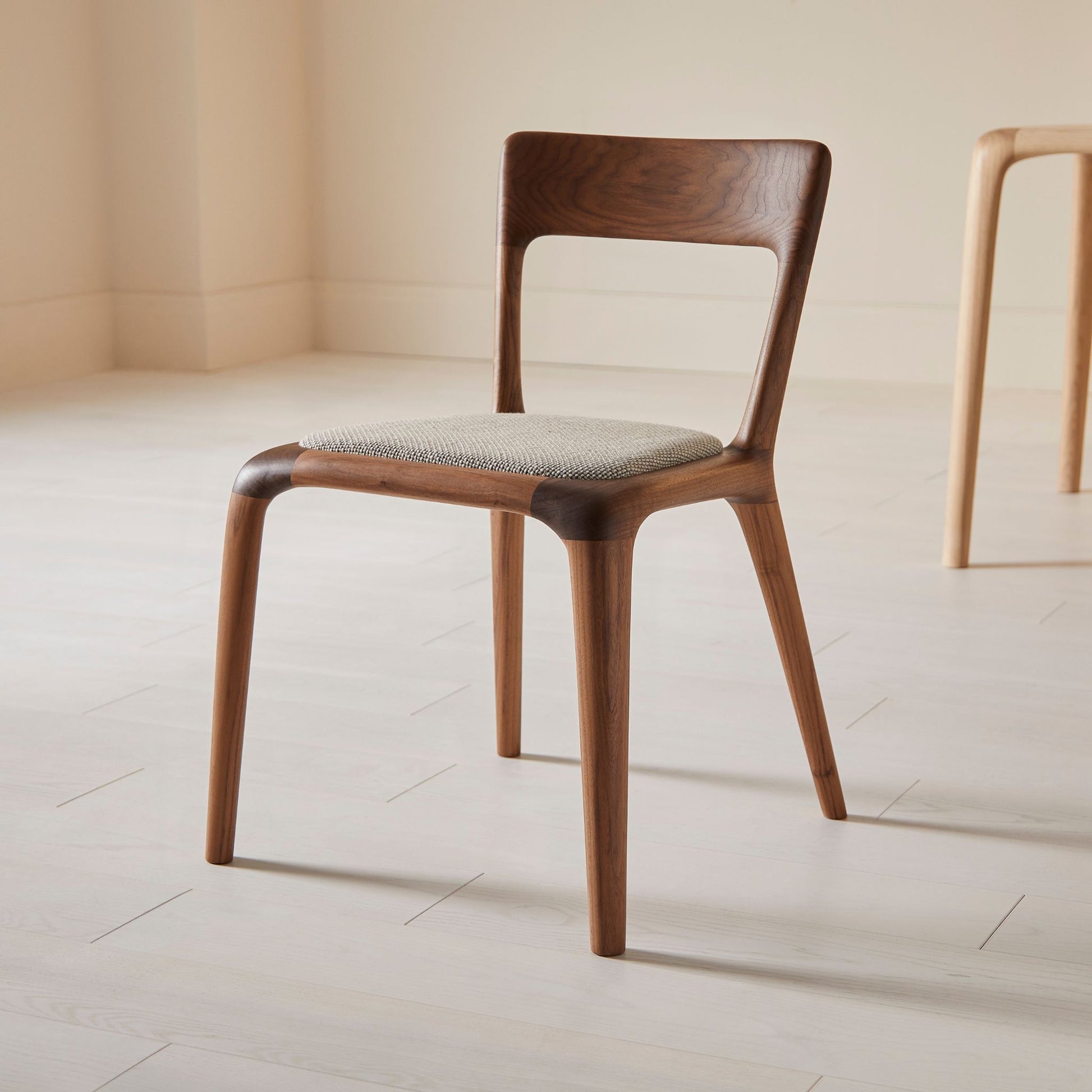 Flow dining chair in walnut with an upholstered seat