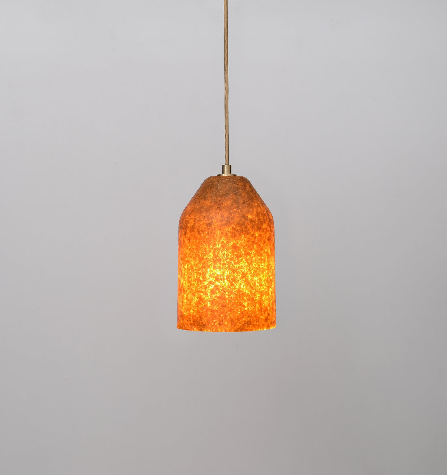 Pendant light with orange glass shade on a gray background